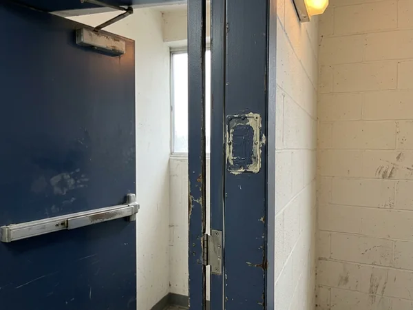 Before: stairwell fire door with painted label and oversize gap